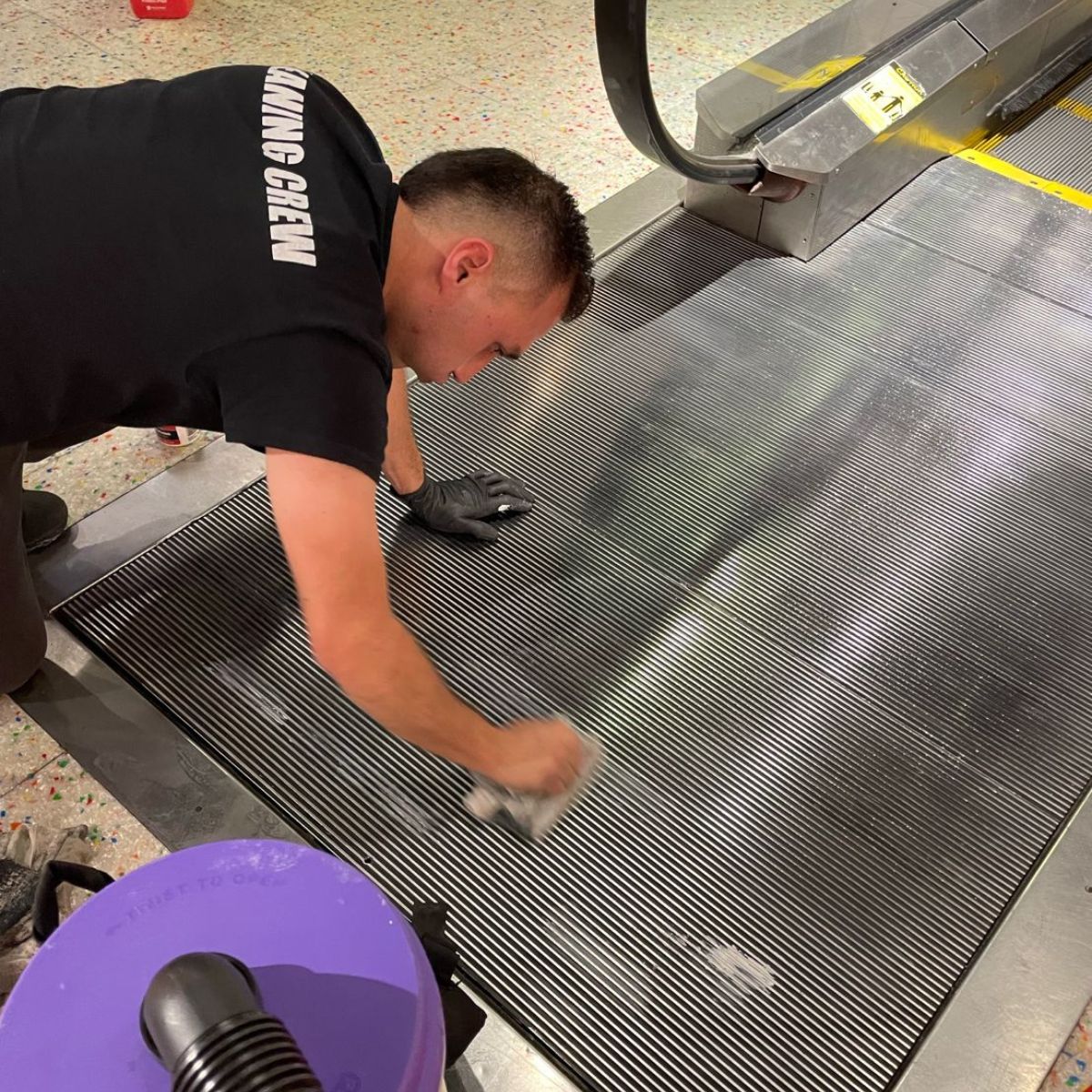 Cleaning technician cleaning stone floors and escalator landing .
