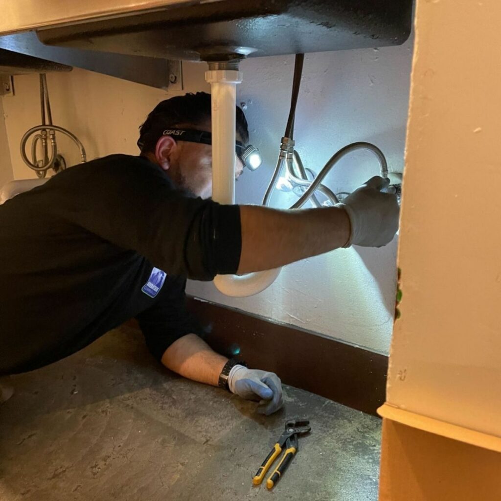 Plumber maintaining sink and faucet in restroom