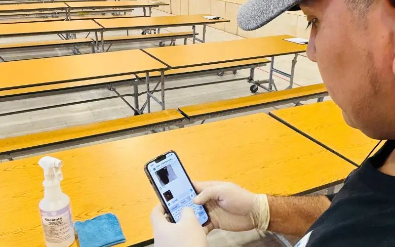 Cleaner looking at school classroom cleaning checklist in mobile app