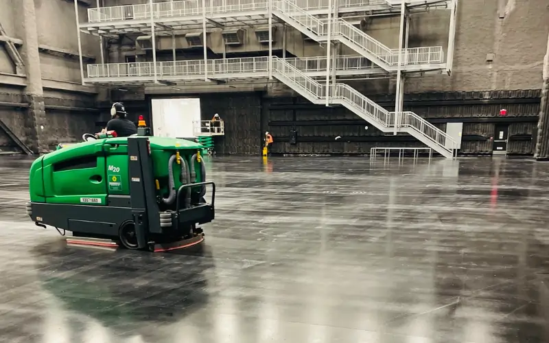 The Warehouse Cleaning Guide - Cleaner on industrial ride-on scrubber cleaning open warehouse floor